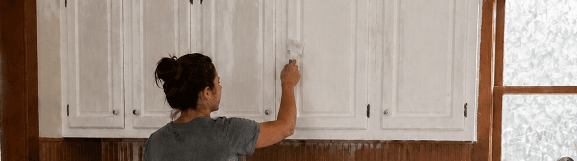 A homeowner painting cabinet doors in a kitchen.