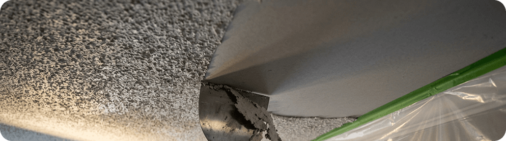 A tradesperson flattening a ceiling after texture removal.